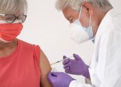A senior woman receiving a COVID-19 booster or vaccine from a healthcare worker or doctor