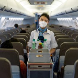 A flight attendant serving drinks on a plane