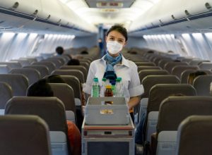 A flight attendant serving drinks on a plane