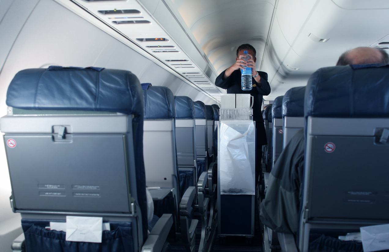 A flight attendant grabbing a plastic water bottle during service on a flight