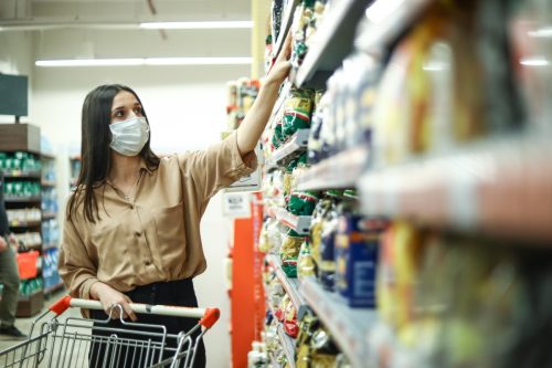 Frau kauft im neuen normalen Supermarkt mit Corona-Virus ein