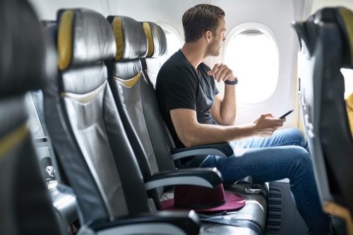 Man sitting on plane holding phone