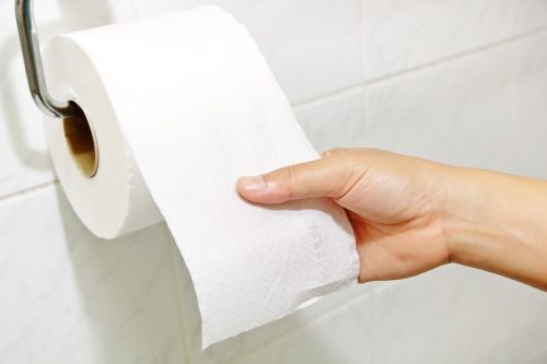 close up of woman's hand pulling toilet paper