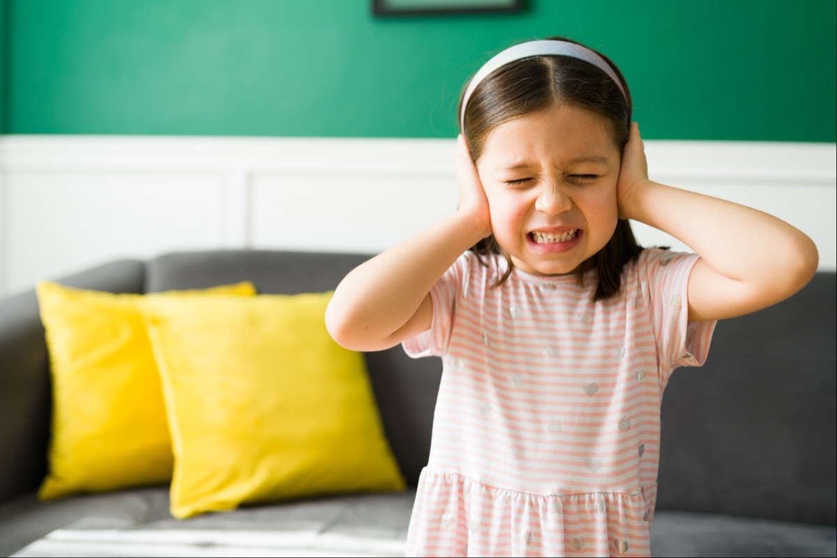 young girl in living room covering ears