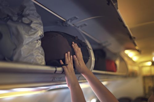 Hand putting bag into the overhead bin on plane