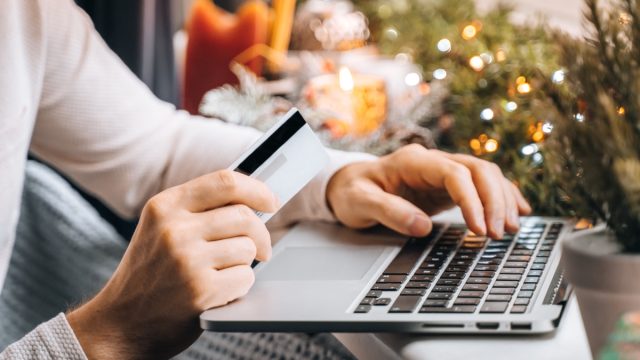 man shopping for holiday gifts online using card
