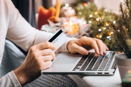 man buying holiday gifts online using card