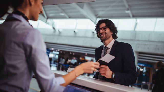 A man handing a boarding pass or plane ticket to a gate agent at the airport