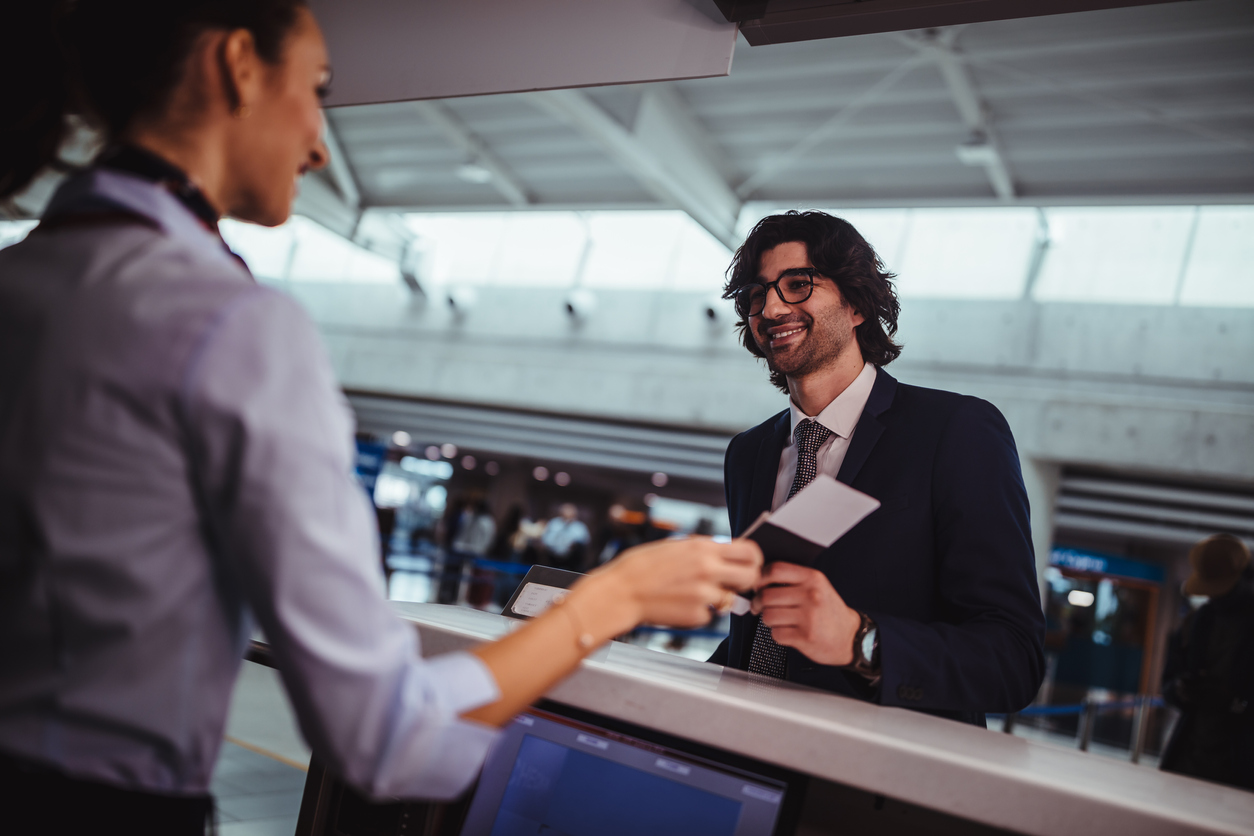 Một người đàn ông đưa thẻ lên máy bay hoặc vé máy bay cho nhân viên cửa khẩu tại sân bay