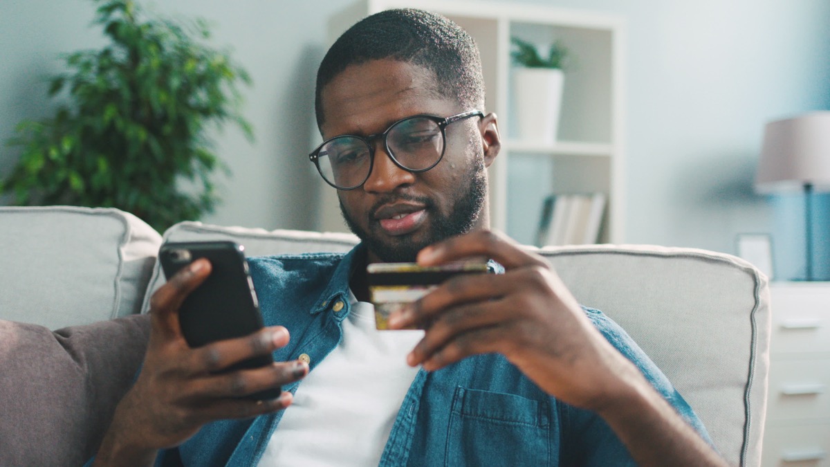 young man with glasses shopping with credit card on his phone