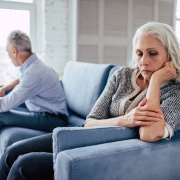 older couple sitting on couch arguing