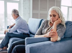 older couple sitting on couch arguing