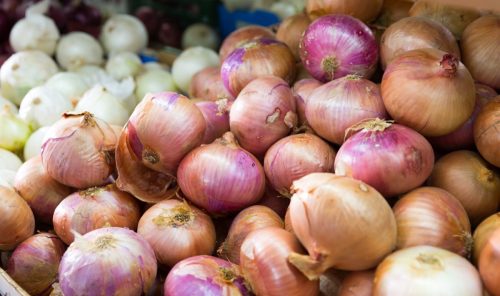 Pile of different onion varieties on market counter