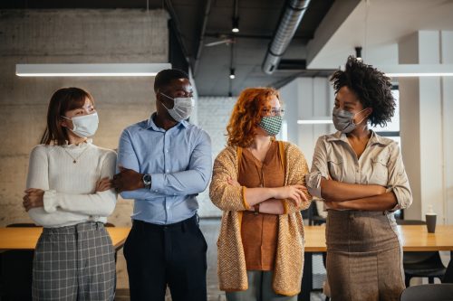 Ein Team von Kollegen, die Masken tragen, um zu verhindern, dass das Corona-Virus im Büro steht