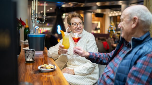 A senior couple raising their cocktails to one another in a bar