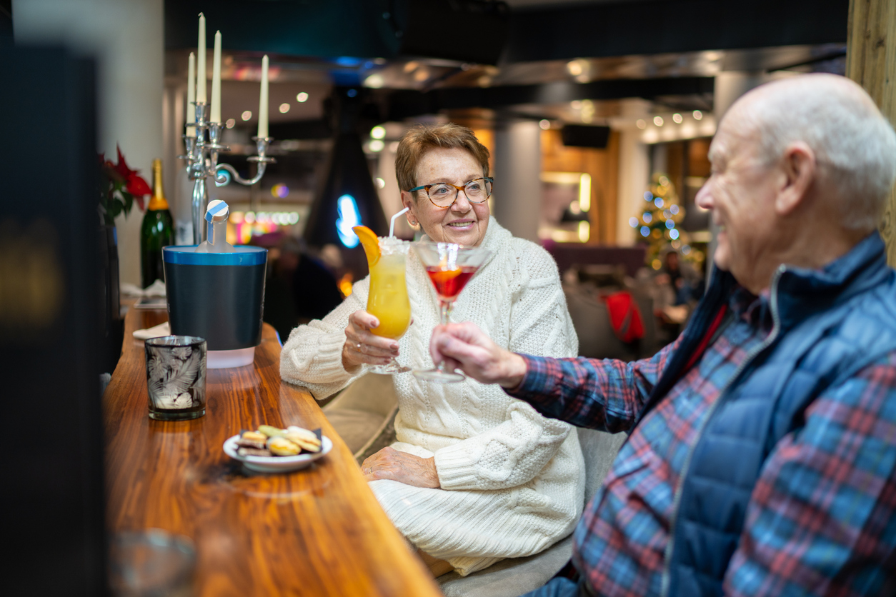 An elderly couple raising their cocktails in a bar
