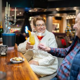 A senior couple raising their cocktails to one another in a bar