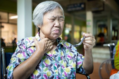 older woman putting her hand to her neck and looking uncomfortable