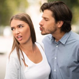 Woman rejecting man trying to kiss her
