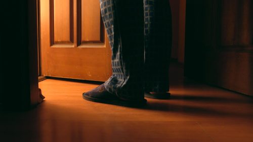 man's legs and feet standing outside open door