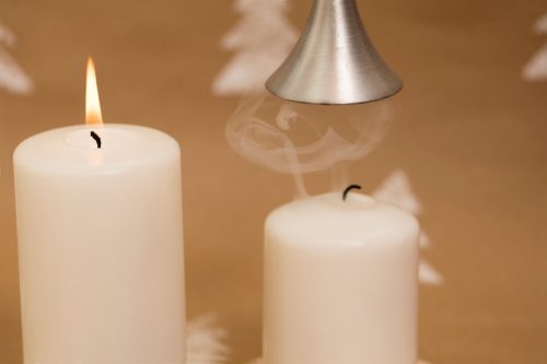 candle extinguished with a candle snuffer and a lit candle next to it