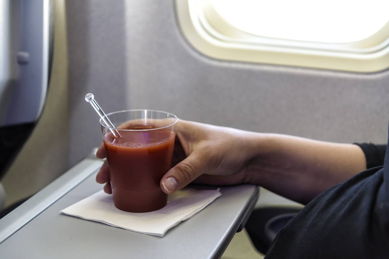 A person drinking a Bloody Mary on a plane