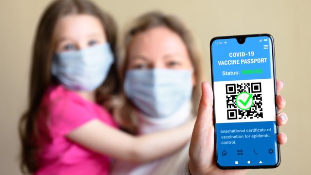 mother and daughter showing proof of vaccination on phone