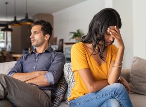 upset 30-something couple arguing on couch