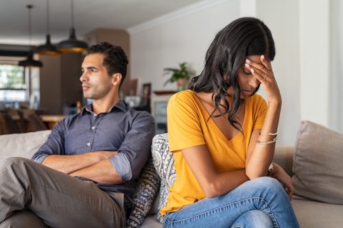 upset 30-something couple arguing on couch