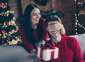 A woman surprising her husband with a holiday gift
