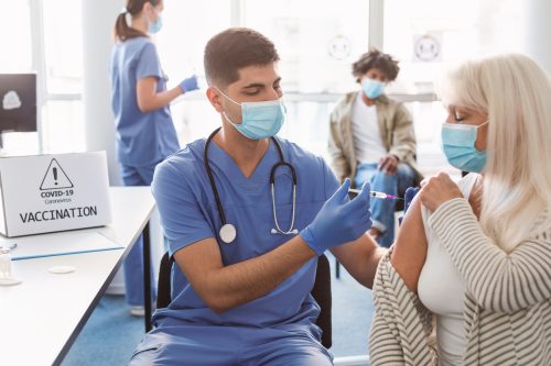 A senior woman receiving a COVID-19 vaccine or booster from a healthcare worker