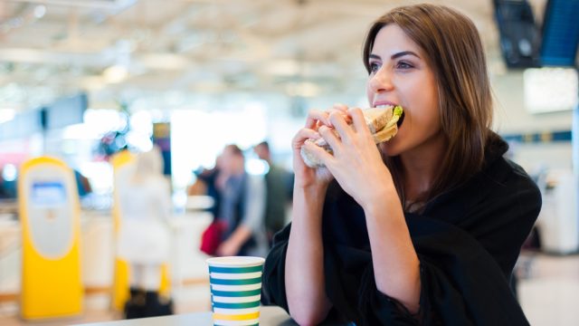 A young woman eating a sandwich in the airport