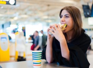 A young woman eating a sandwich in the airport