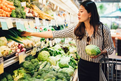 A young woman shopping for vegetables in a grocery store