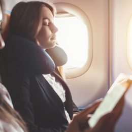 A woman sleeping on a plane with a neck pillow