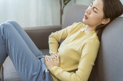 young woman on couch with stomach pain