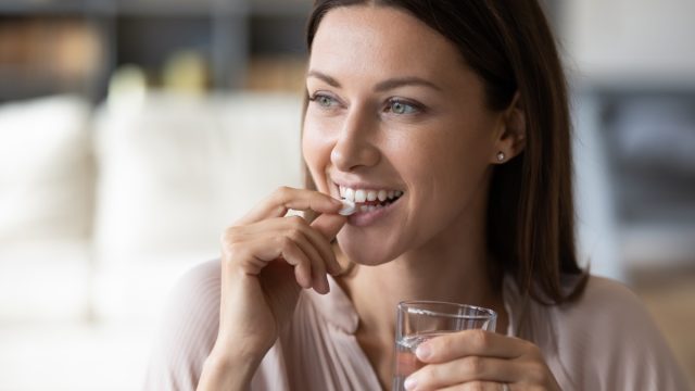 young woman taking supplement pill