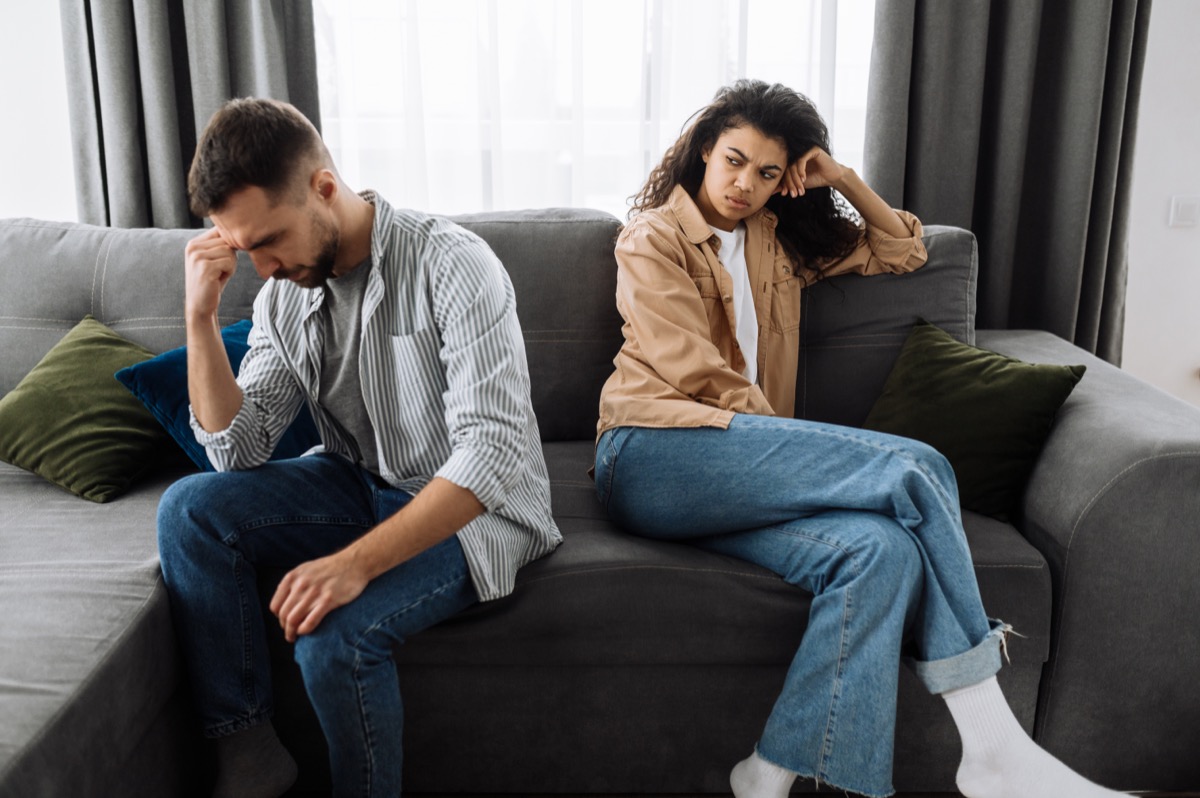 woman sitting on couch with boyfriend looking upset