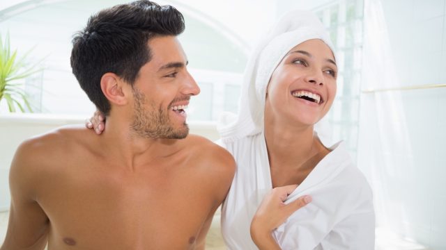 Attractive couple laughing in towels at home in bathroom