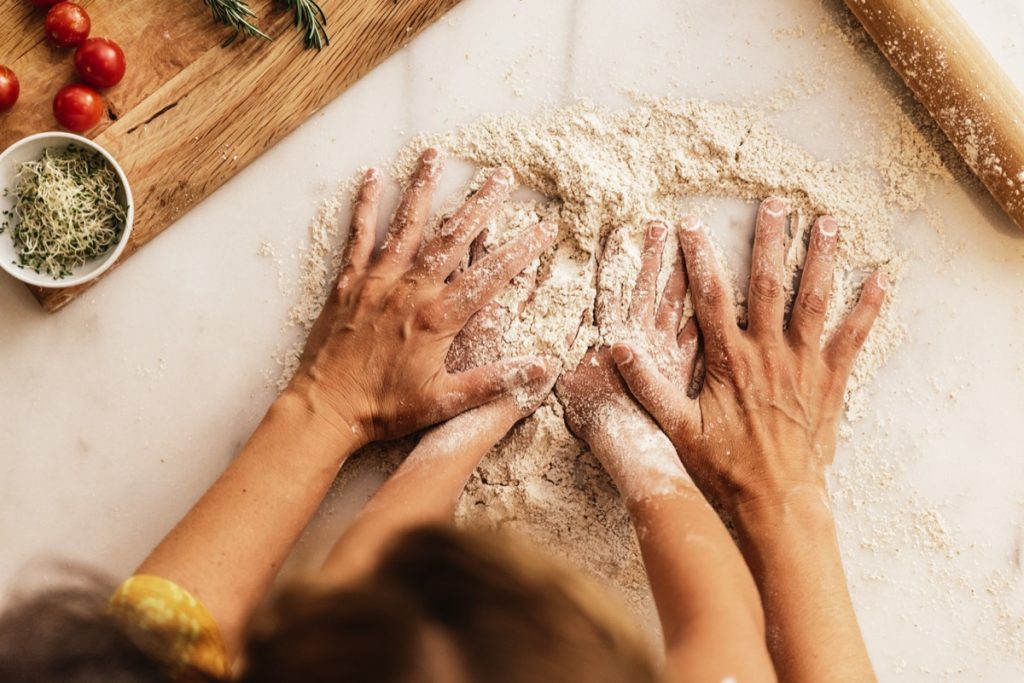 Closeup of mother and child's hands kneading dough