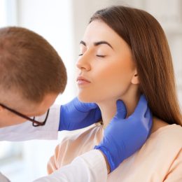 Doctor examining young woman's neck