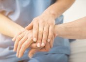 Composite image of nurse holding patient hand on a bed