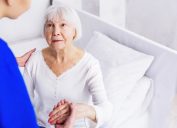 Older woman standing up with help of nurse