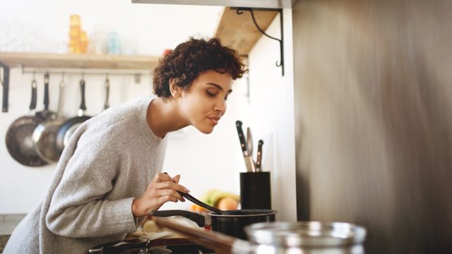 Young woman stirring pot while cooking