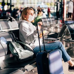 A female passenger in a medical mask is waiting for a flight at the airport.