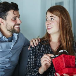 A woman opening a gift she doesn't like from her partner.