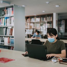 university student studying in library observing social distancing