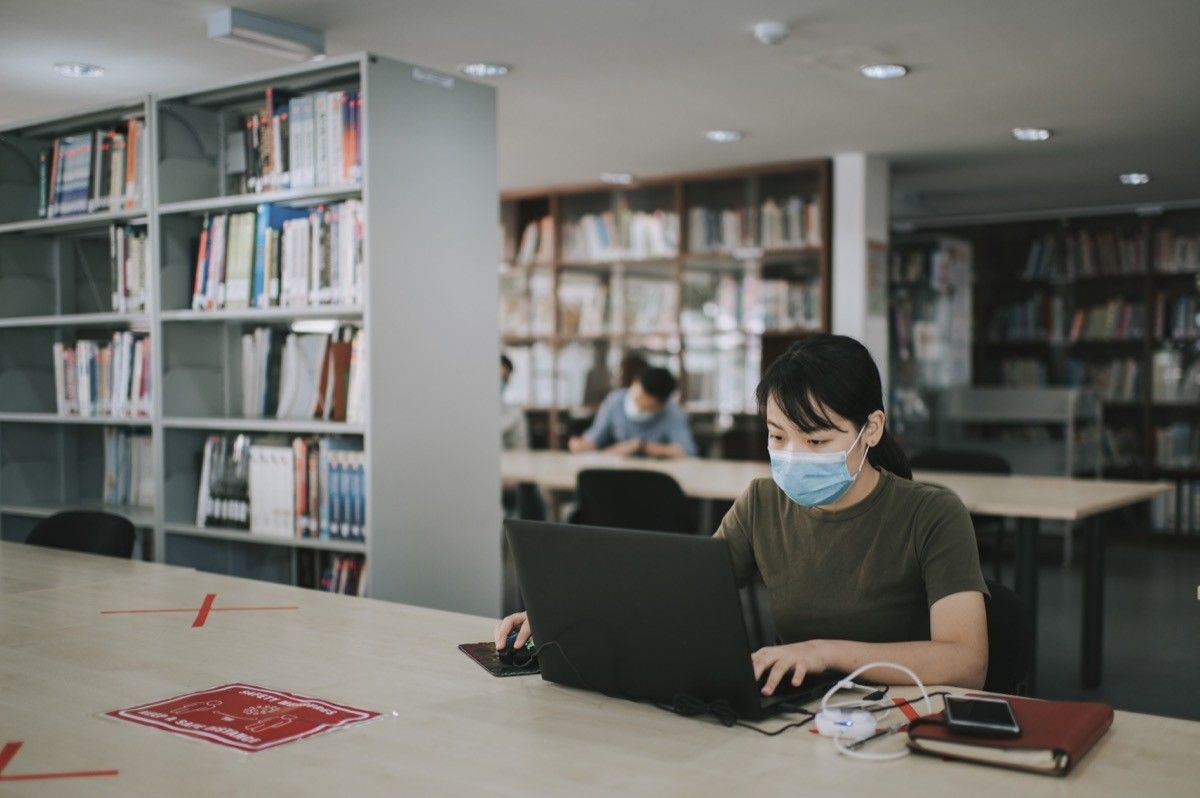 university student studying in library observing social distancing