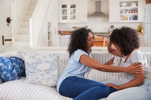 Mãe conversando com filha adolescente infeliz no sofá