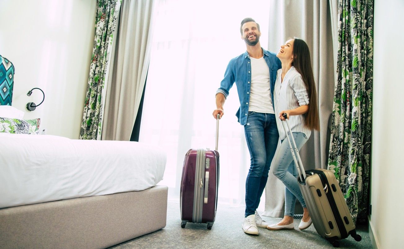 A young couple standing in a hotel room hugging